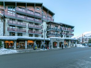 A multi-story hotel with balconies, stone facade, and shops on the ground floor. - **Comfortable Apartment, WiFi, Parking, South-Facing, Heart of Val-d'Isère, Close to Slopes** (Val-d'Isère)
