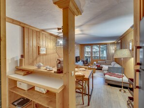 A wooden interior with a dining area, sofa, and a view of the outside.