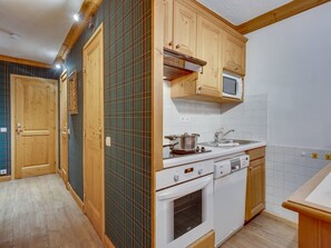 A kitchen with wooden cabinets, a microwave, an oven, and a sink.