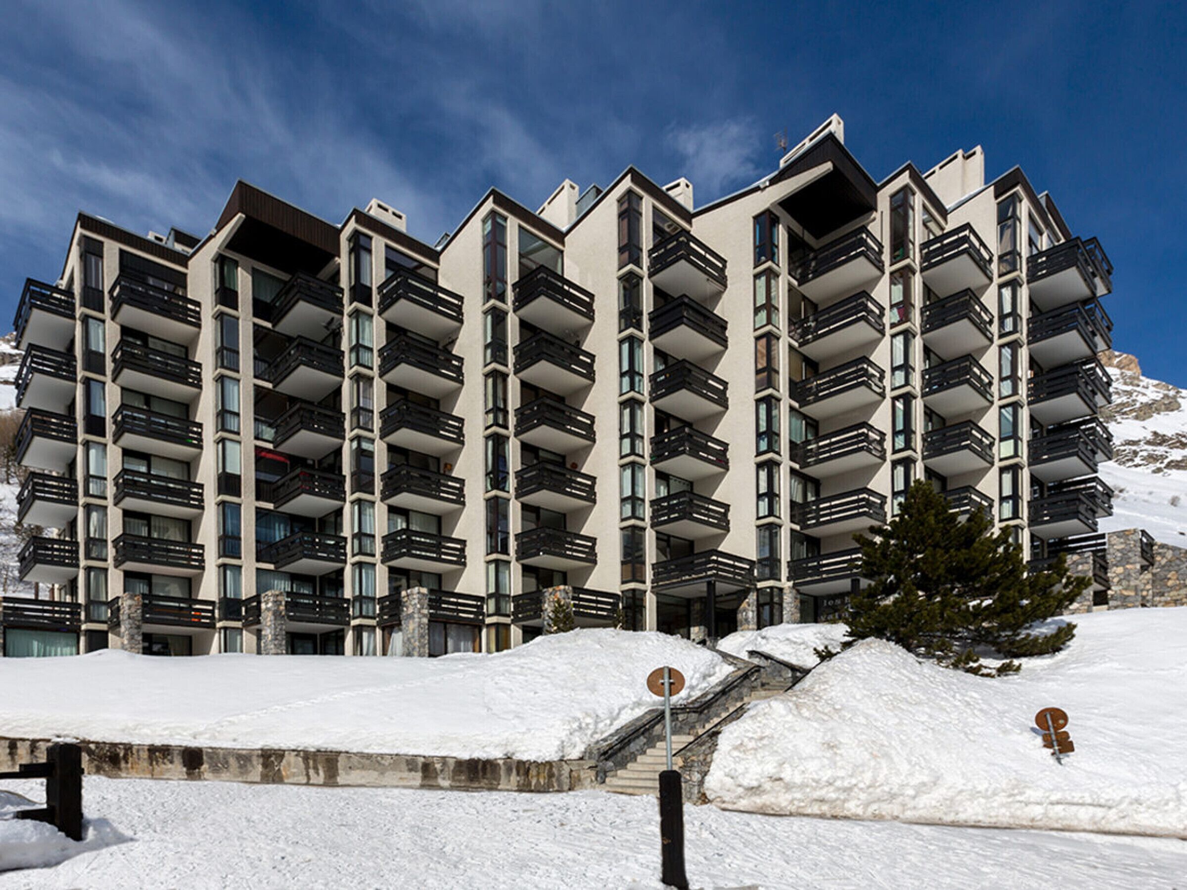 A multi-story hotel with balconies, a snow-covered landscape, and a clear sky.