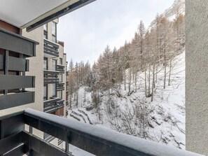 A modern building with a balcony overlooking a snowy hillside with trees.