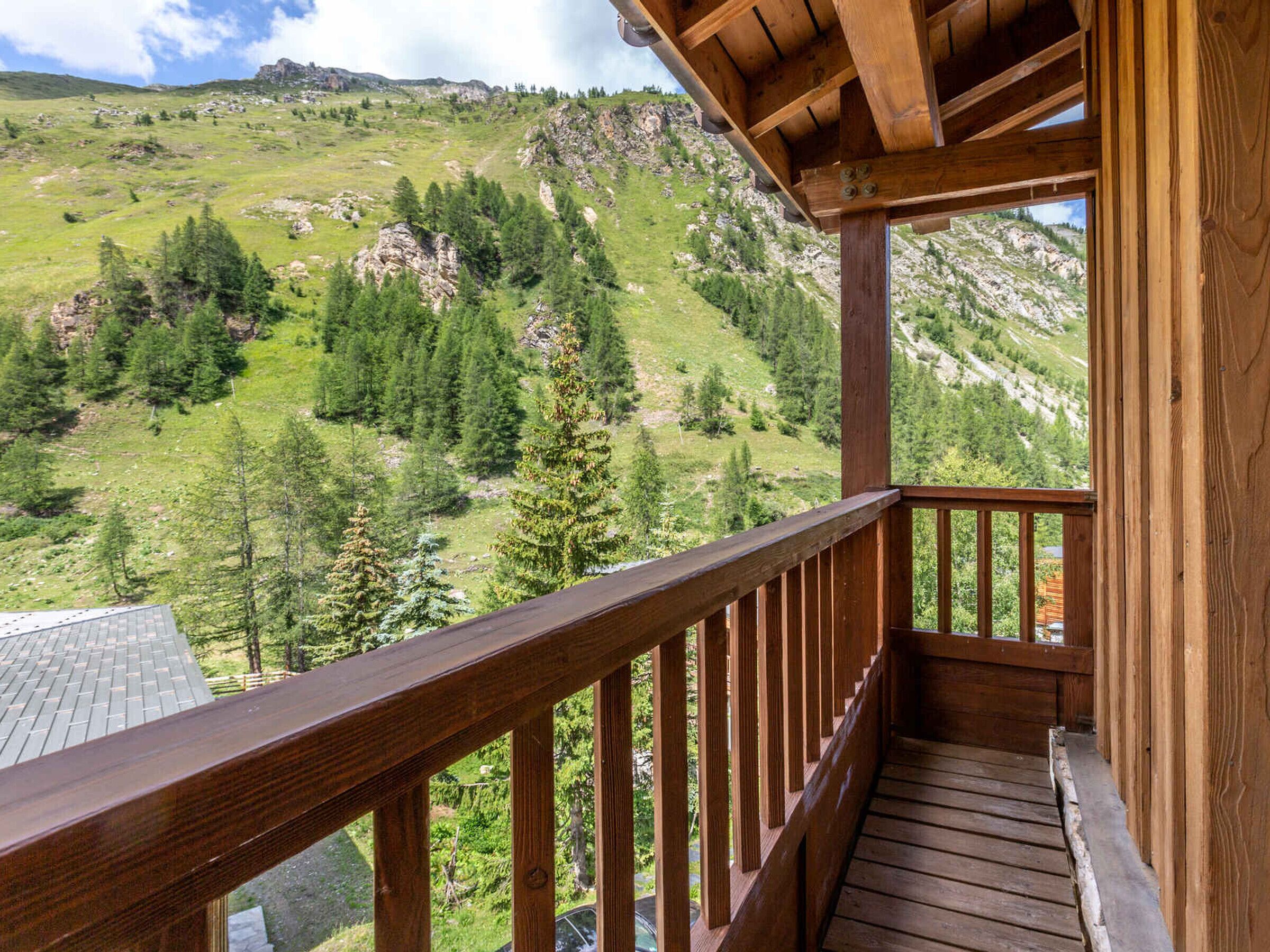 A wooden balcony with a view of a mountainous landscape.