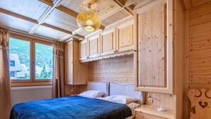 Ein Schlafzimmer aus Holz mit einem Bett, Nachttisch und einem Fenster mit Vorhängen.