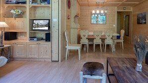Ein gemütliches Holzhaus-Interieur mit Essbereich, Fernseher und Kamin.