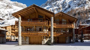 Eine mehrstöckige Holzhütte mit Steinsäulen, Balkonen und einer Garage.