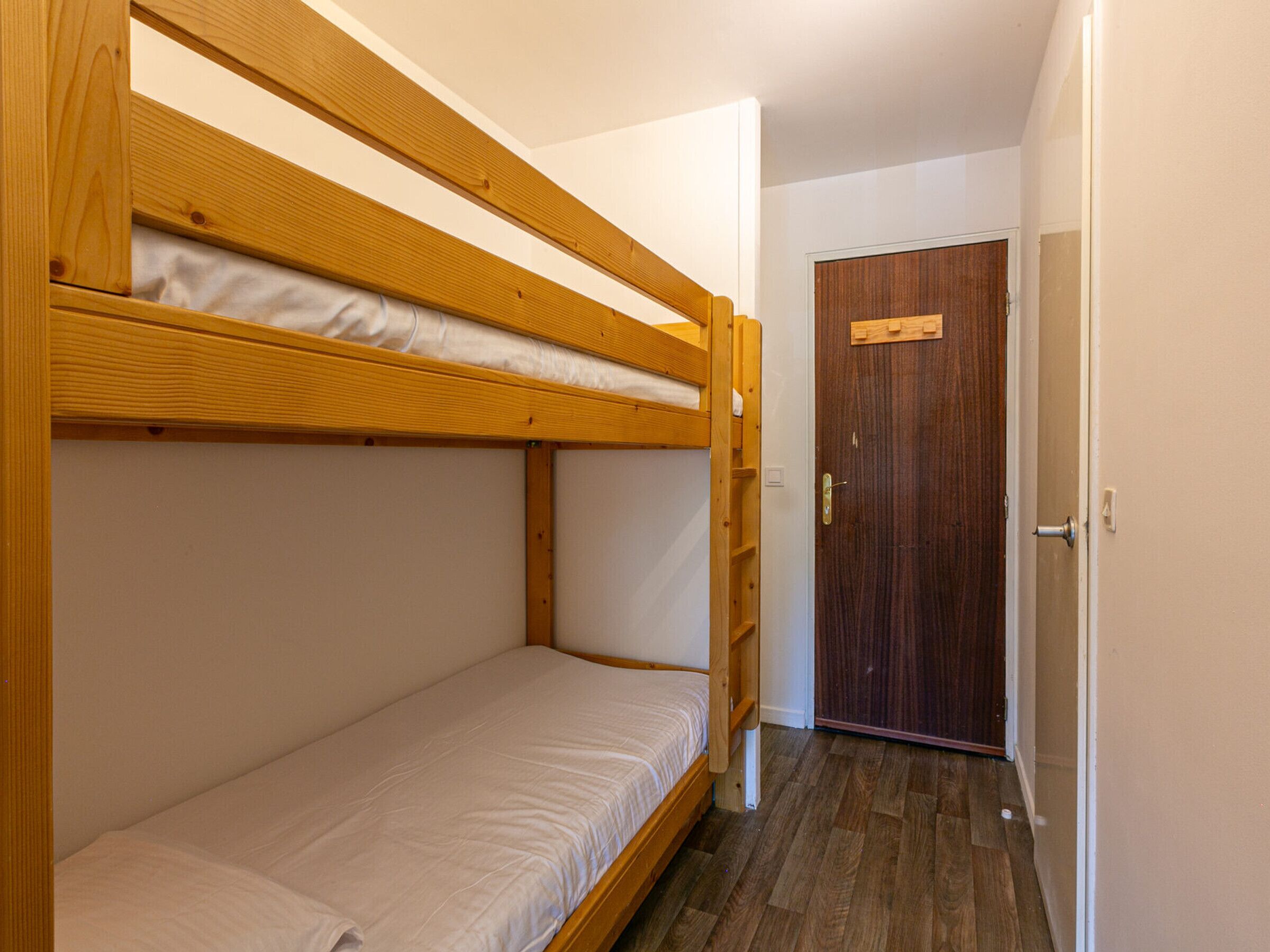 A small, narrow room with a bunk bed and a door.