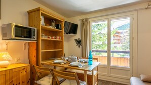 A cozy kitchen with wooden cabinets, a microwave, and a dining table set for four.
