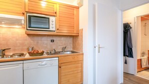 Eine kompakte Küche mit Holzschränken, einer Mikrowelle, einem Spülbecken und einem Geschirrspüler.