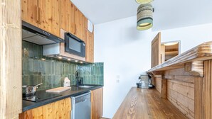 A modern kitchen with wooden cabinetry, a stainless steel dishwasher, a microwave, and a coffee machine.