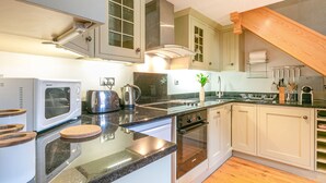 Eine moderne Küche mit Einbauofen, Mikrowelle und Toaster. Es gibt eine Holzausziehtafel und ein Spülbecken mit Wasserhahn.