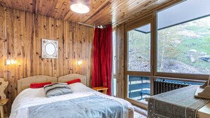 A wooden-paneled bedroom with a bed, a window, and a radiator.