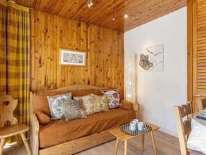 A wooden-paneled room with a sofa, a small table with mugs, and a wall with a framed picture and a decorative item.