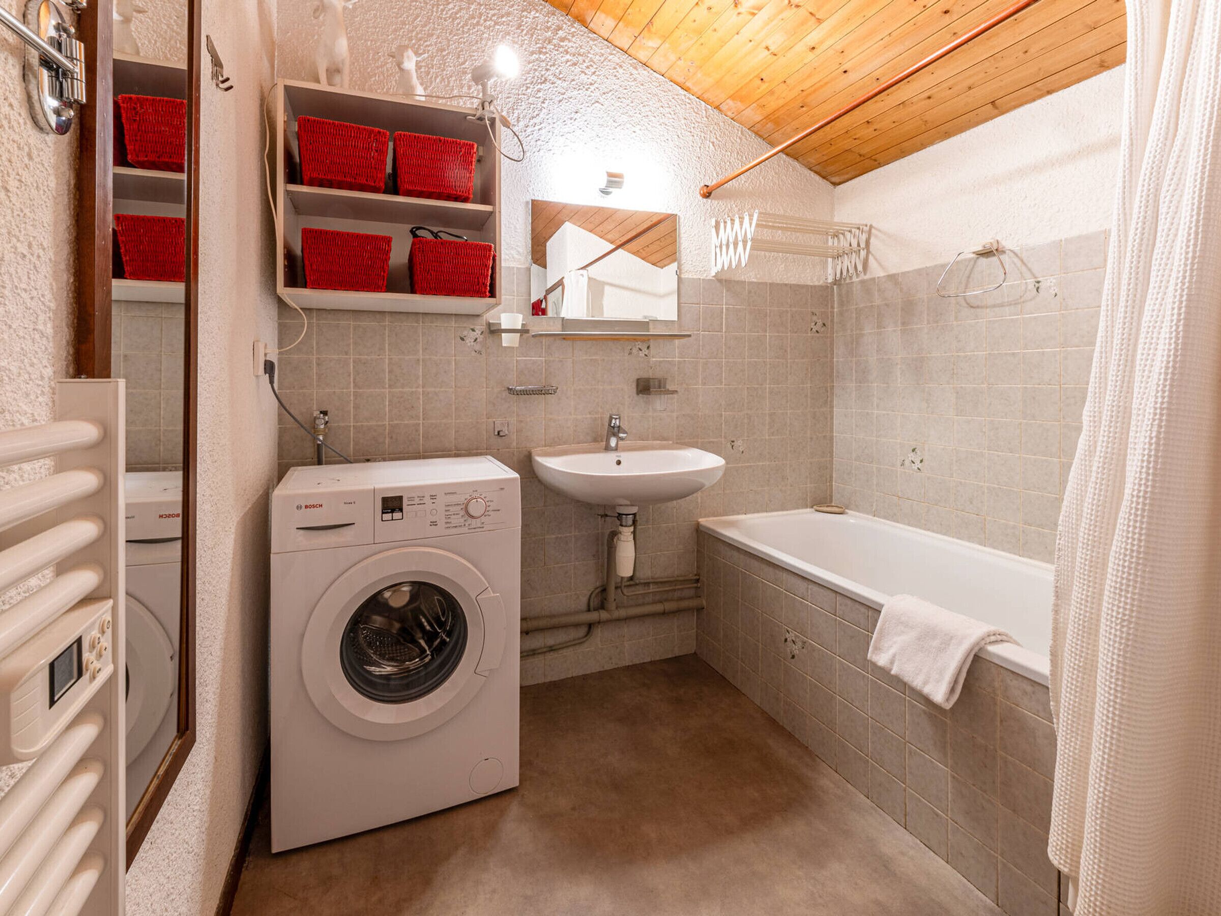 A compact bathroom with a washing machine, sink, and bathtub.