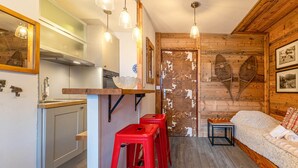 Eine gemütliche Küche mit Holzelementen, einem roten Hocker und einem kleinen Tisch mit Schachbrett.