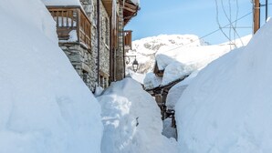 A narrow snow-covered street flanked by stone buildings with wooden balconies. - Rustic Mountain-Style Apartment in Chalet, Village Center, Ski-In/Ski-Out (Val-d'Isère)