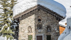 A stone building with a wooden door and windows, surrounded by snow. - Rustic Mountain-Style Apartment in Chalet, Village Center, Ski-In/Ski-Out (Val-d'Isère)