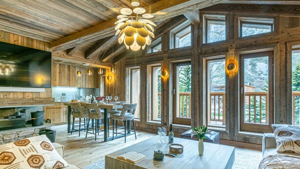 A spacious living area with a large wooden ceiling, a dining table, and multiple windows offering a view of the outdoors. - Elegant Apartment in New Residence with Ski-in/Ski-out Access in Val-d'Isère (Val-d'Isère)