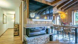 A rustic interior with a stone fireplace, wooden beams, and a dining area with chairs and a table. - Elegant Apartment in New Residence with Ski-in/Ski-out Access in Val-d'Isère (Val-d'Isère)