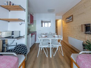 A compact kitchen with a dining area, white cabinetry, and a wooden floor.
