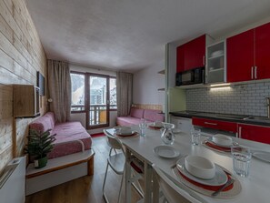 A compact room with a dining area, kitchenette, and a cozy seating area with a view of a snowy landscape.