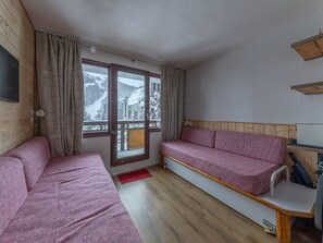 Quarto com duas camas, piso de madeira, janela com vista para montanhas cobertas de neve e teto de madeira.