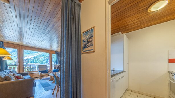 Ett rum med ett träpanelat tak, en soffa, ett matbord och utsikt över omgivningen.