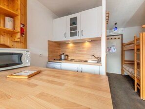 A compact kitchen with a microwave, stove, and wooden cabinets.