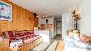 Ein gemütliches Zimmer mit einer Holzdavonia, einem Esstisch für zwei Personen und einer Küchenzeile mit Mikrowelle und Schränken.