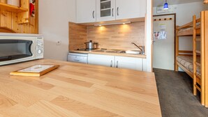 Eine kleine Küche mit Mikrowelle, Herd und Holzschränken.