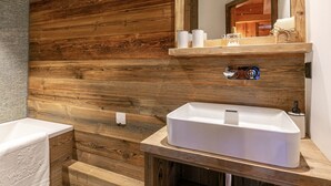Une salle de bain avec un mur en bois, un lavabo blanc et un miroir au-dessus.
