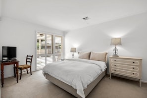 Une chambre à coucher comprenant un lit, un bureau, une chaise, une commode et un téléviseur.