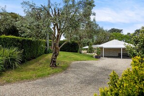 A gravel driveway leading to a building with a white roof and a covered patio area.