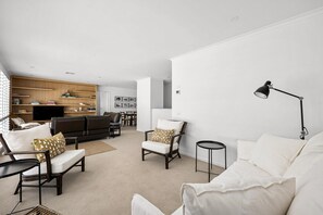 Un salon moderne avec un canapé, des fauteuils, une table basse et un téléviseur.