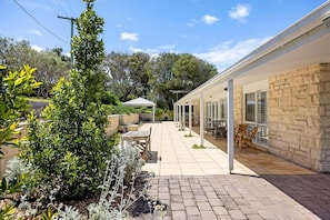 A covered outdoor patio with stone walls, a pergola, and outdoor furniture.