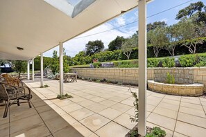 A covered patio area with outdoor furniture, a stone wall, and a landscaped garden.