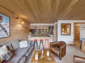 A cozy living room with a sofa, a coffee table with playing cards, and a wooden ceiling. - Luxurious 4-Room Apartment with South-Facing Balcony in Central Val-d'Isère (Val-d'Isère)