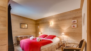Ein Zimmer mit Holzwandverkleidung, einem Bett, zwei Nachttischlampen und einem Sessel.