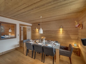 A dining area with a wooden ceiling, a large mirror, and a table set for four. - Luxurious 4-Room Apartment with South-Facing Balcony in Central Val-d'Isère (Val-d'Isère)