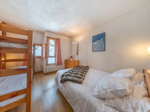 A bedroom with a bunk bed, a single bed, a dresser, a mirror, and a painting on the wall.