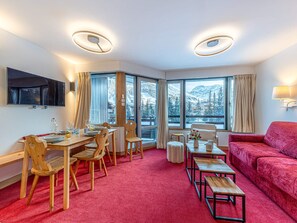 Ein modernes Hotelzimmer mit Essbereich, einer Couch und großen Fenstern mit Blick auf die Berge.