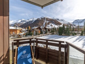Eine Holterrasse mit Blick auf ein Bergresort, inklusive Gebäude und schneebedeckten Pisten.