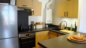 Eine kleine Küche mit Kühlschrank, Backofen, Mikrowelle und Spüle.