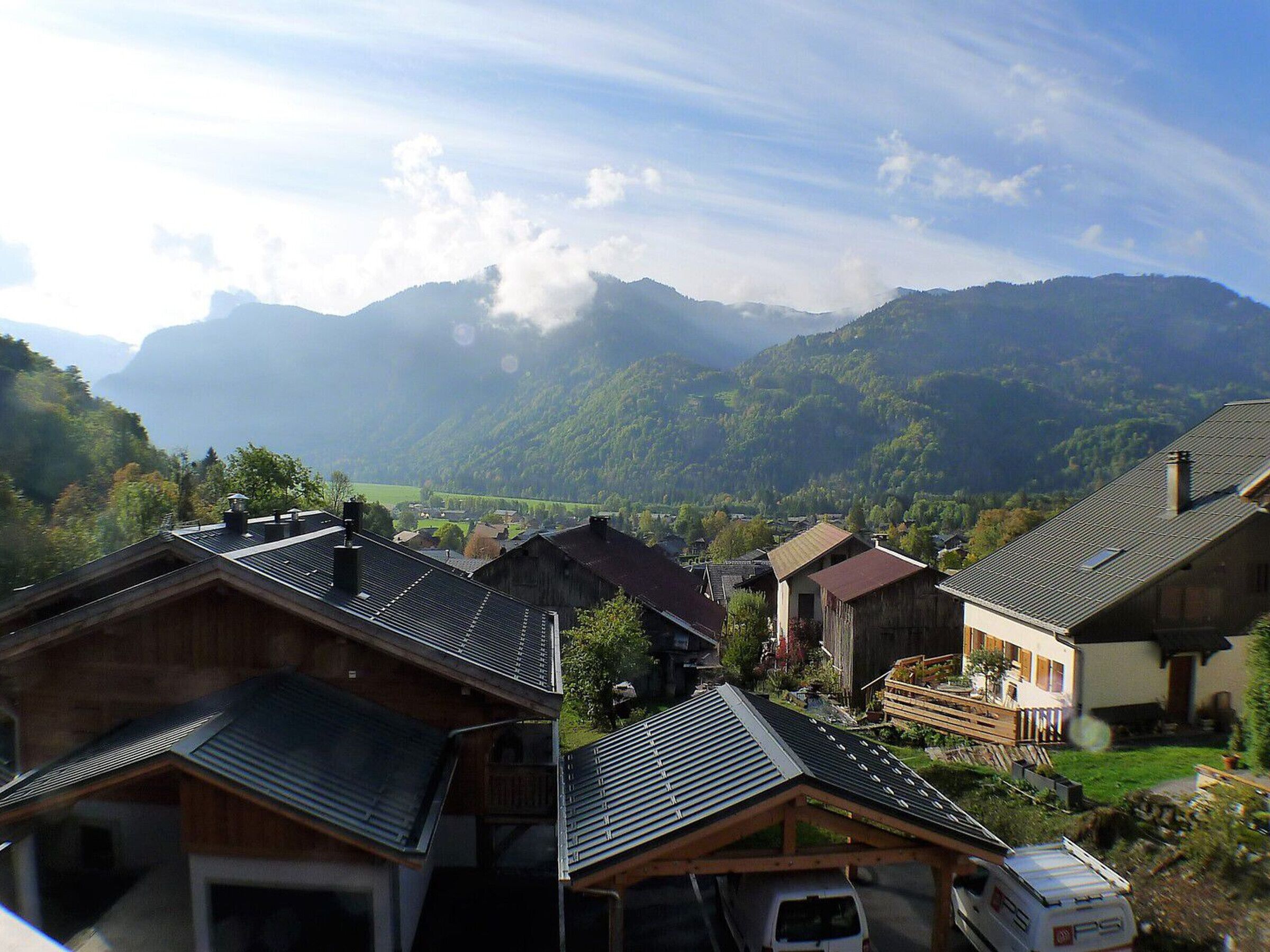 Un village de montagne doté de maisons traditionnelles en bois et offrant une vue dégagée sur les collines environnantes.