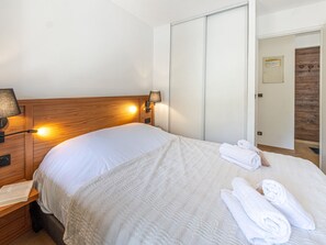 A neatly made bed with a white comforter and a rolled towel on the side.