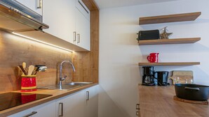 Une cuisine moderne avec des meubles en bois, un évier en acier inoxydable et une machine à café.