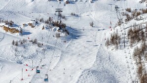 Une piste de ski enneigée, avec des remontées mécaniques et des skieurs.