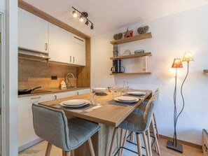 A modern kitchen with wooden cabinets, a dining table set for four, and a floor lamp.