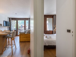 A room with a bed, a wooden dining table with chairs, and a view of a mountain landscape through a large window. - Renovated ski-in/ski-out apartment with parking and wifi in Val-d'Isère (Val-d'Isère)