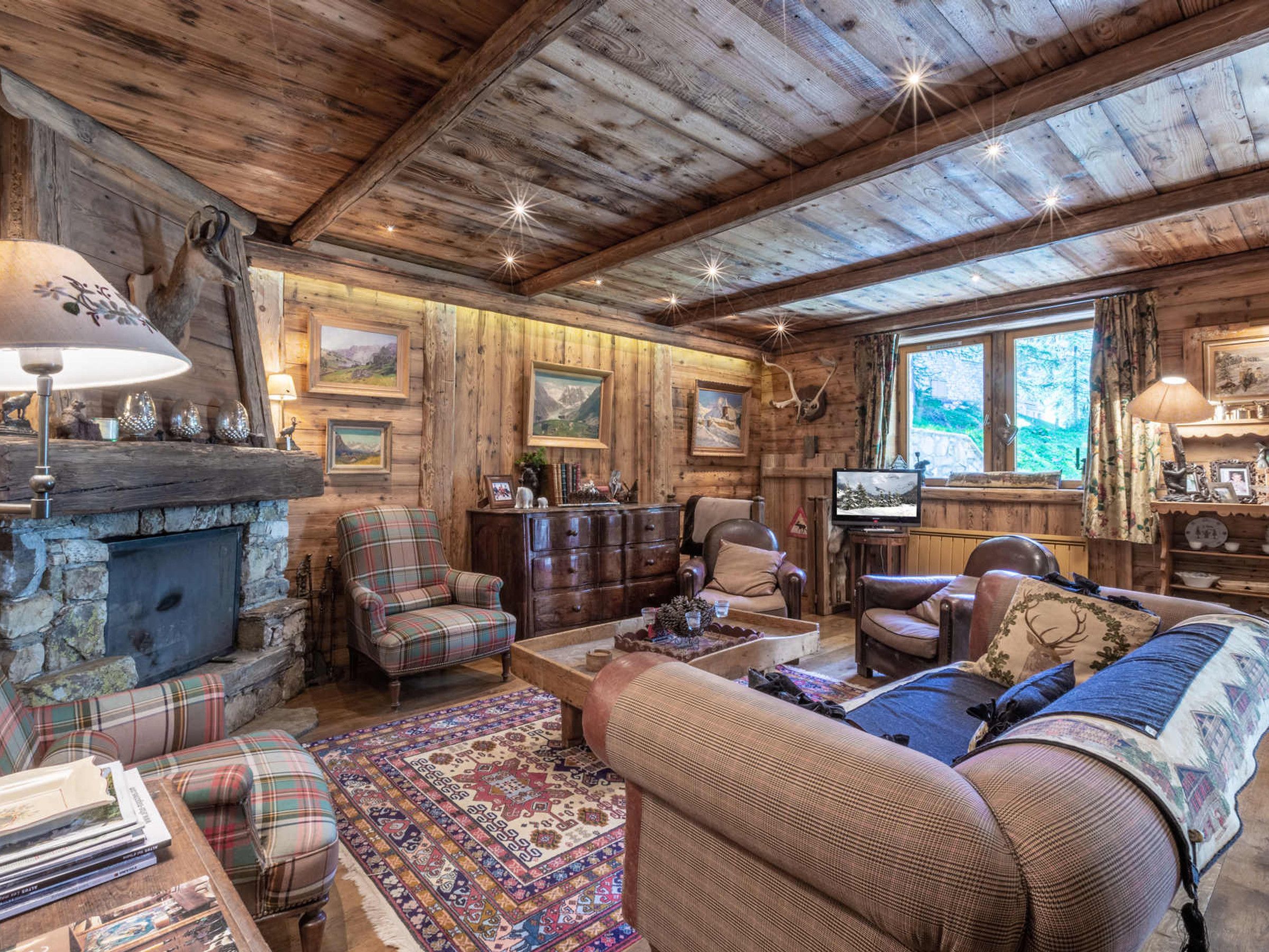 A cozy cabin interior with a fireplace, plaid furniture, and a television.