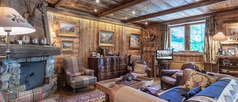 A cozy cabin interior with a fireplace, plaid furniture, and a television.